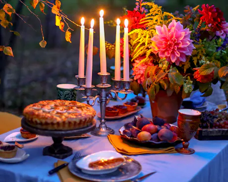 Evening outdoor dinner party with candlelit tablescape, seasonal flowers, fruit, and rustic summer entertaining decor