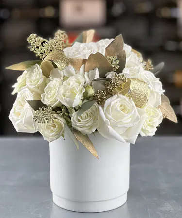 Holiday floral arrangement of white roses with gold ribbon and metallic accents Griffins Floral Design