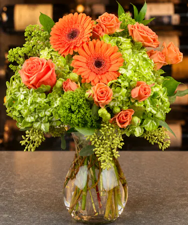 Orange gerbera daisies and mandarin roses with green hydrangea in modern clear vase – Columbus Ohio florist